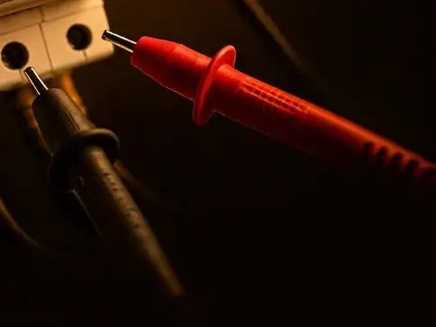 Rote und schwarze Prüfspitze an den Anschlussklemmen eines Schaltgeräts.